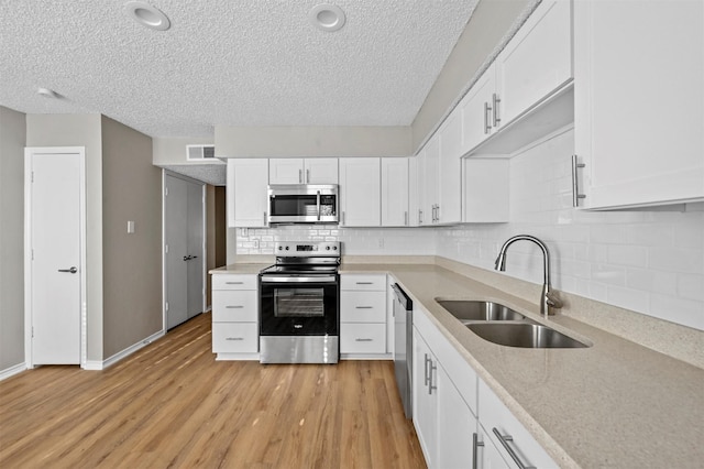 kitchen with visible vents, light wood finished floors, a sink, appliances with stainless steel finishes, and white cabinetry