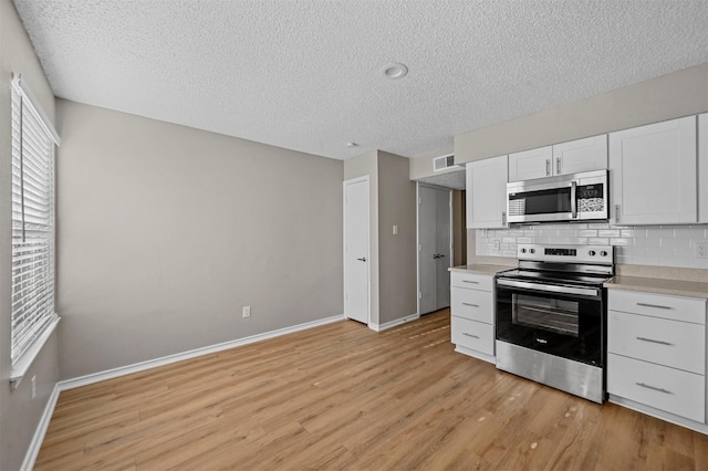 kitchen with light countertops, light wood-style floors, backsplash, and stainless steel appliances