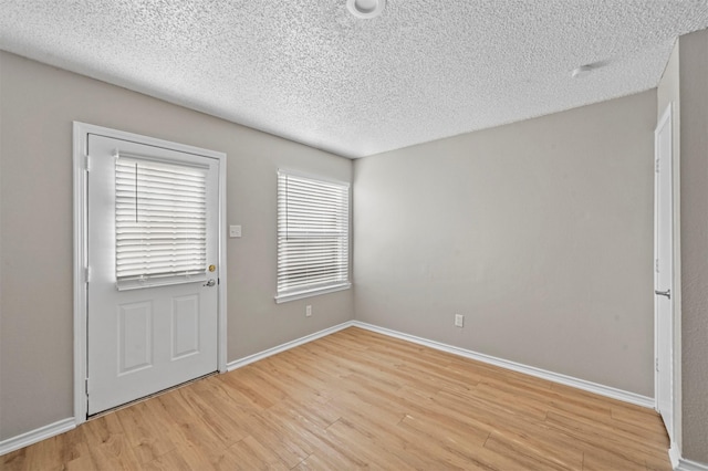 foyer entrance featuring baseboards, a textured ceiling, and light wood finished floors