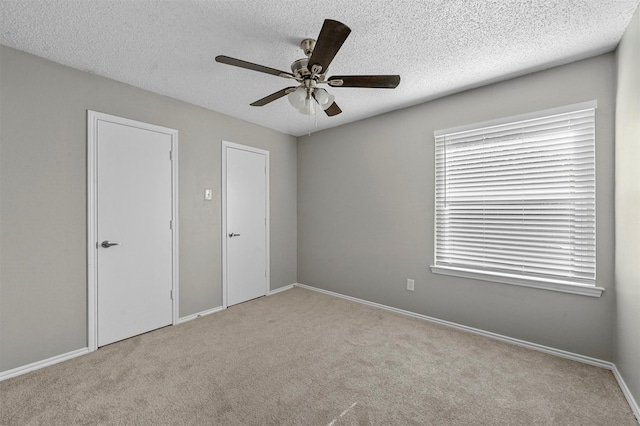 unfurnished bedroom featuring carpet flooring, a ceiling fan, baseboards, and a textured ceiling