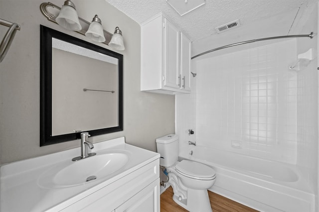 full bathroom featuring visible vents, toilet, a textured ceiling, wood finished floors, and vanity