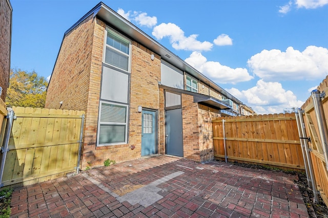 back of property featuring a patio area, brick siding, and fence