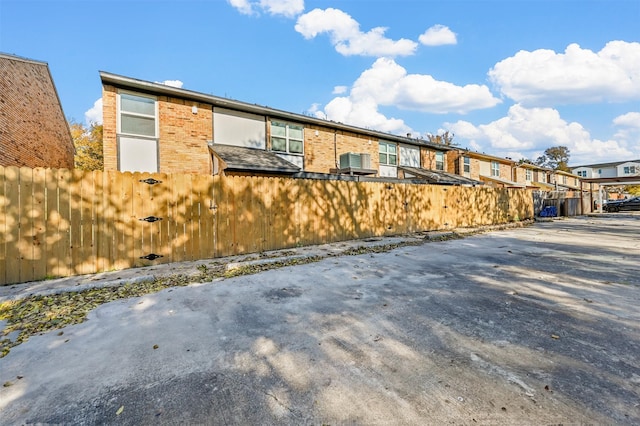 view of side of home featuring a residential view, brick siding, and fence