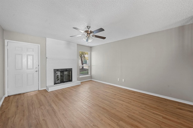 unfurnished living room featuring a fireplace, baseboards, light wood finished floors, and ceiling fan