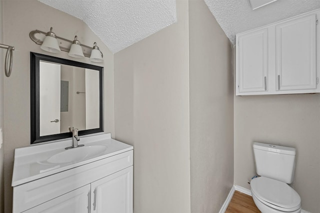 half bathroom featuring toilet, a textured ceiling, vanity, and vaulted ceiling