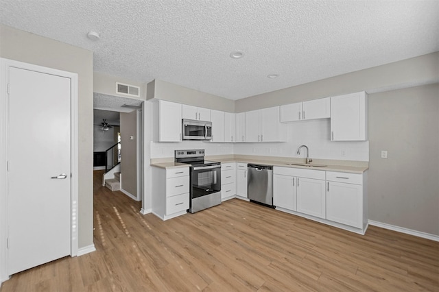 kitchen with visible vents, a sink, light countertops, light wood-style floors, and appliances with stainless steel finishes