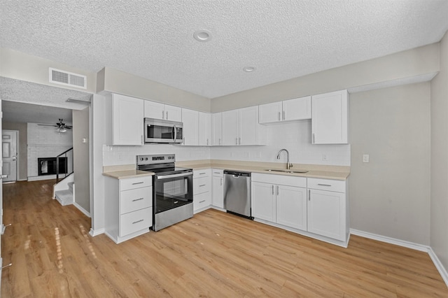 kitchen with light wood-type flooring, visible vents, a sink, stainless steel appliances, and light countertops