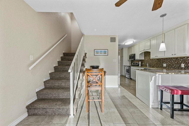 interior space with visible vents, decorative light fixtures, appliances with stainless steel finishes, decorative backsplash, and ceiling fan