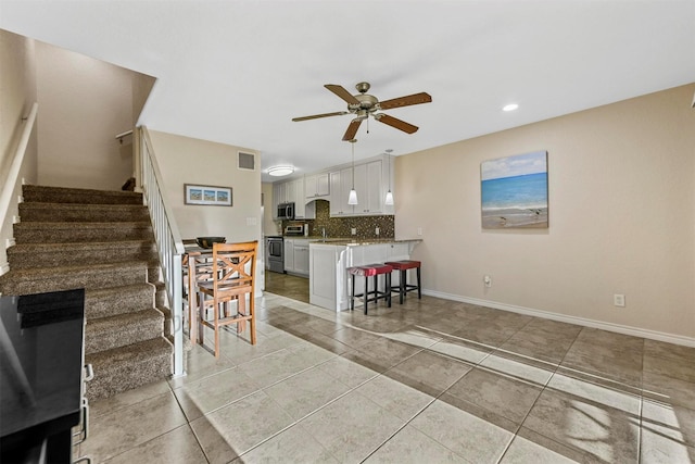 interior space featuring visible vents, a ceiling fan, stairway, light tile patterned flooring, and baseboards