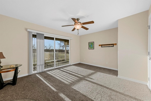 carpeted spare room with a ceiling fan and baseboards