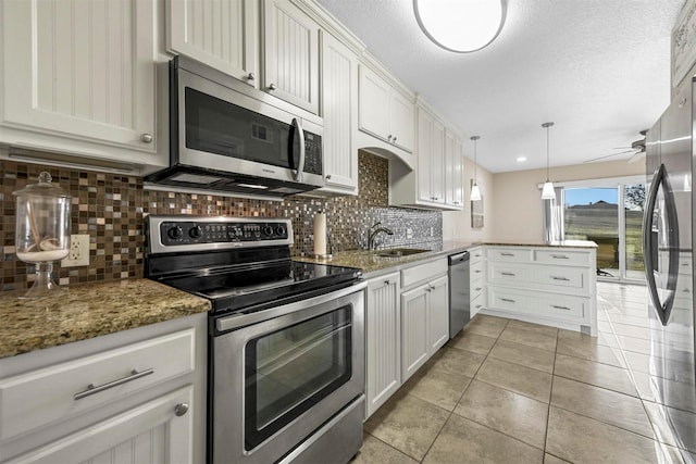 kitchen with backsplash, light tile patterned floors, a peninsula, stainless steel appliances, and a sink