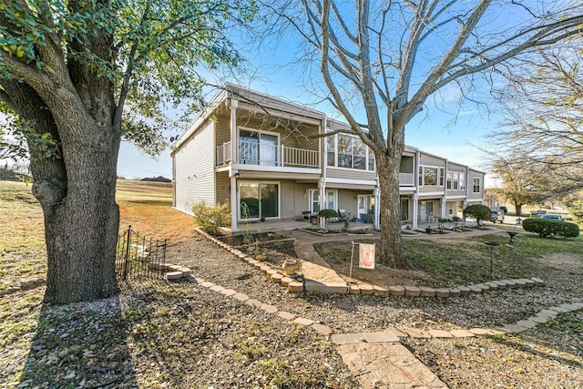 rear view of house featuring a patio and a balcony