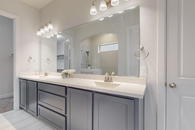 bathroom with double vanity, a tile shower, and a sink