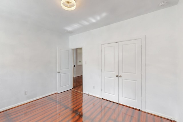 unfurnished bedroom featuring a closet, baseboards, and wood finished floors