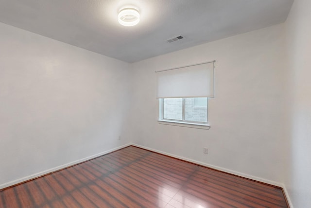 spare room featuring wood finished floors, baseboards, and visible vents