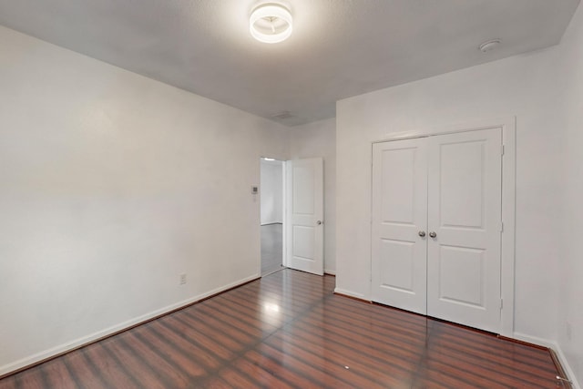 unfurnished bedroom with a closet, baseboards, and wood finished floors