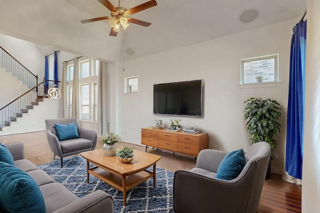 living room with ceiling fan, stairway, a high ceiling, and wood finished floors