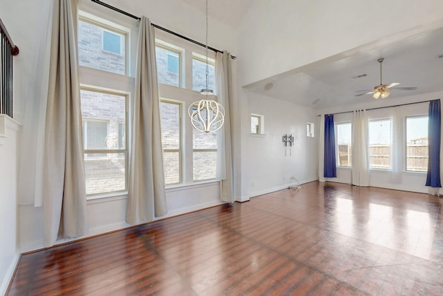 unfurnished living room featuring visible vents, a ceiling fan, wood finished floors, baseboards, and a towering ceiling