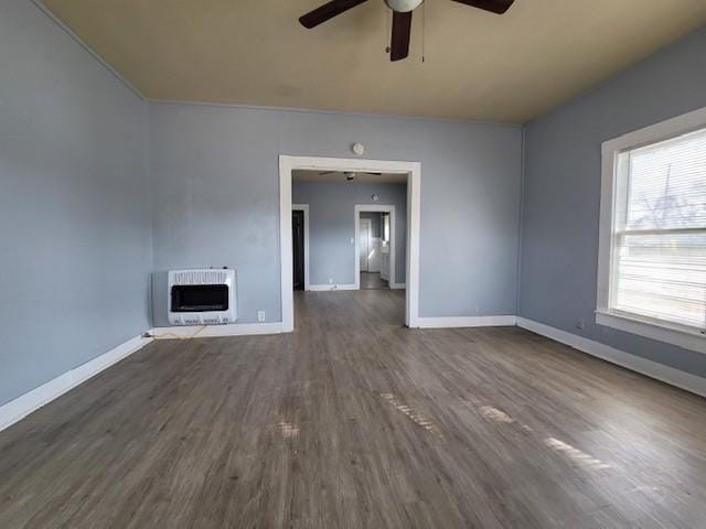 unfurnished living room with dark wood-type flooring, heating unit, a fireplace, and baseboards