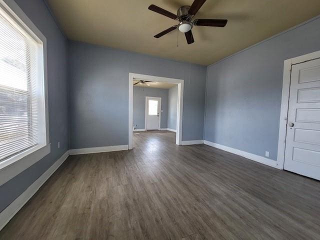 spare room with baseboards, dark wood-style floors, and a ceiling fan