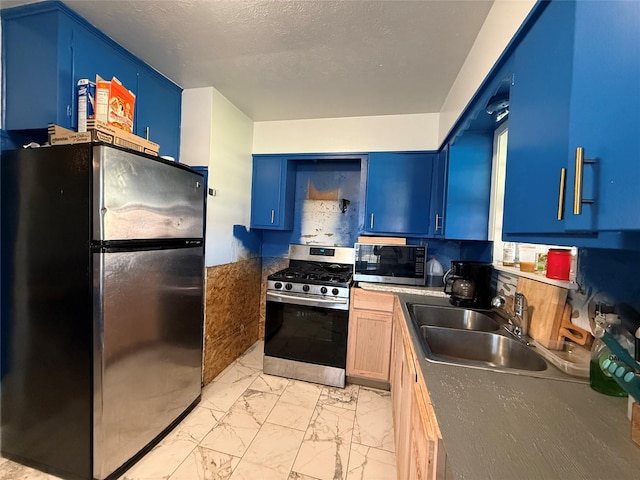 kitchen featuring blue cabinets, marble finish floor, a sink, a textured ceiling, and stainless steel appliances