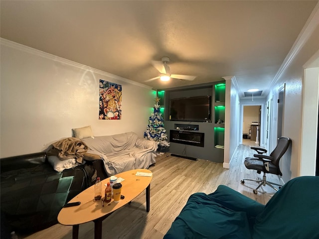 living area with a ceiling fan, attic access, wood finished floors, and crown molding