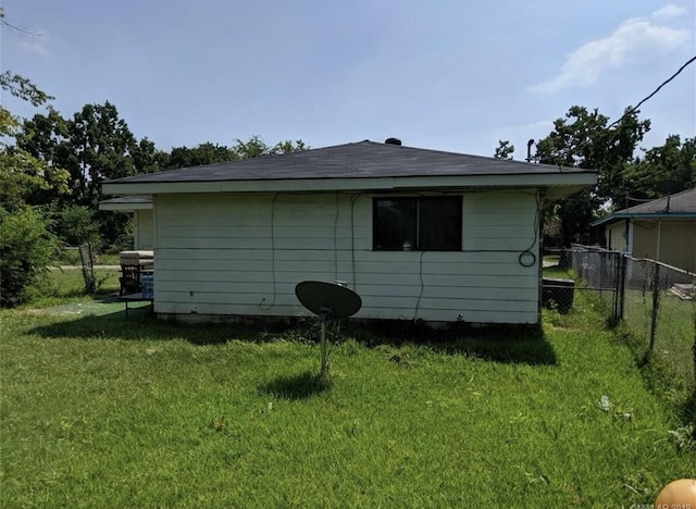 view of side of home featuring a lawn and fence