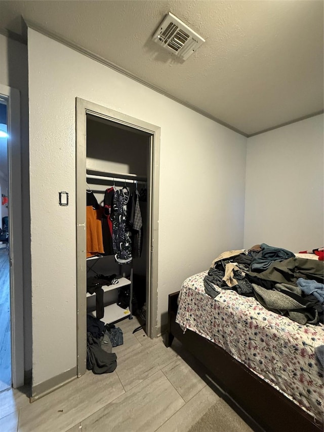 bedroom featuring visible vents, light wood-style floors, a closet, and a textured ceiling