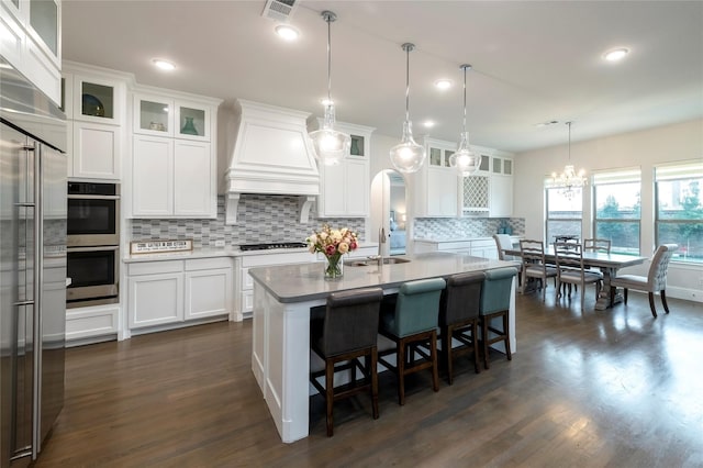 kitchen with visible vents, custom range hood, tasteful backsplash, arched walkways, and appliances with stainless steel finishes