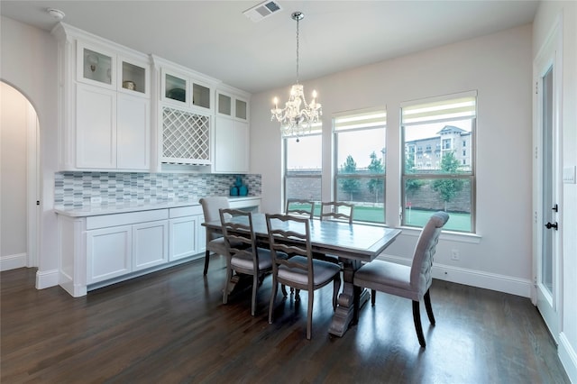 dining space featuring visible vents, baseboards, dark wood finished floors, a chandelier, and arched walkways