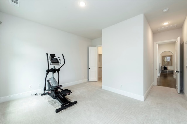 exercise room with visible vents, baseboards, and light carpet