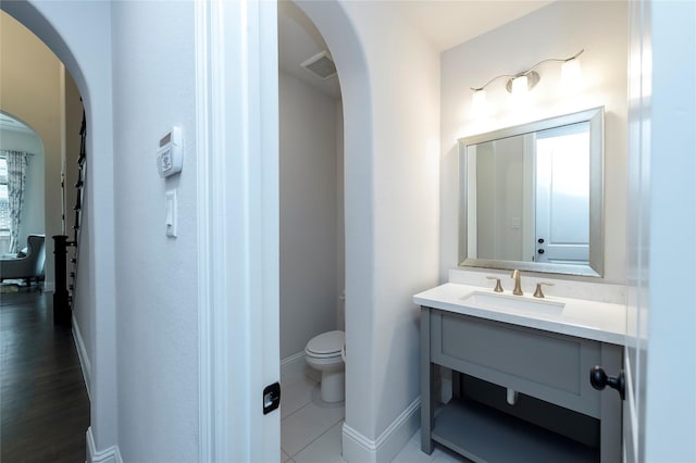 half bathroom featuring visible vents, toilet, vanity, and baseboards