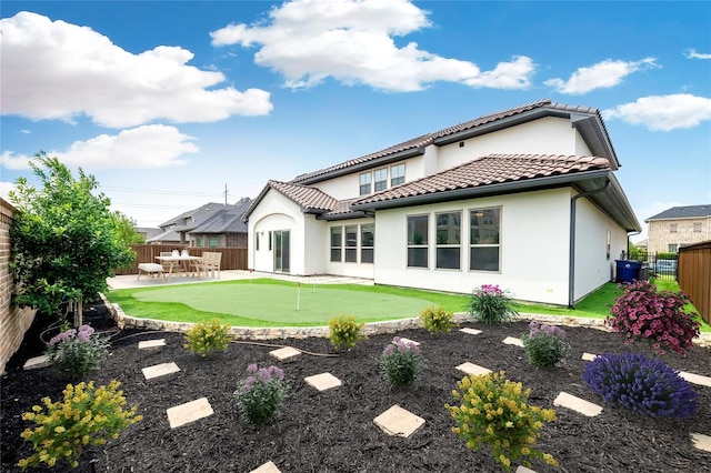 rear view of house featuring stucco siding, a tile roof, a fenced backyard, and a patio area