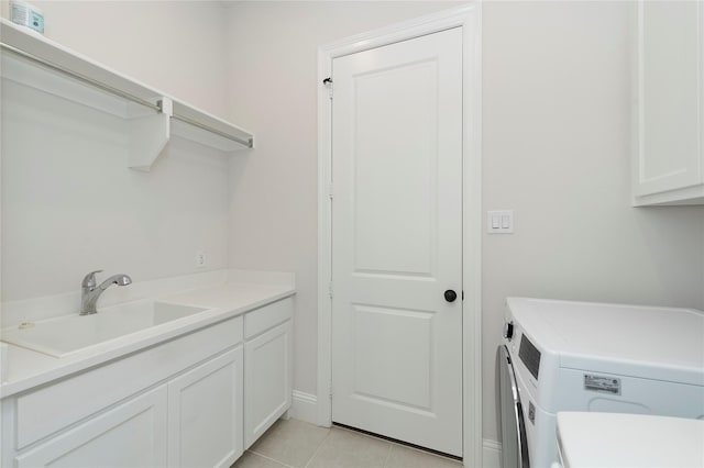 washroom featuring washing machine and clothes dryer, light tile patterned floors, cabinet space, and a sink