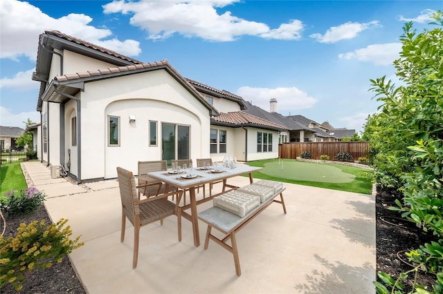 rear view of house with stucco siding, fence, and a patio area