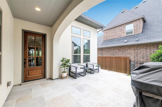 doorway to property featuring brick siding, stucco siding, roof with shingles, and fence