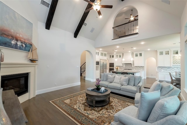 living room with visible vents, stairway, dark wood-style floors, arched walkways, and a glass covered fireplace