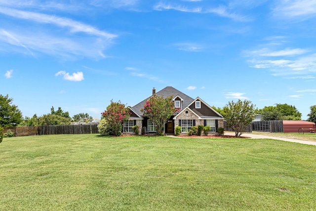 view of front of house with stone siding, a front lawn, and fence