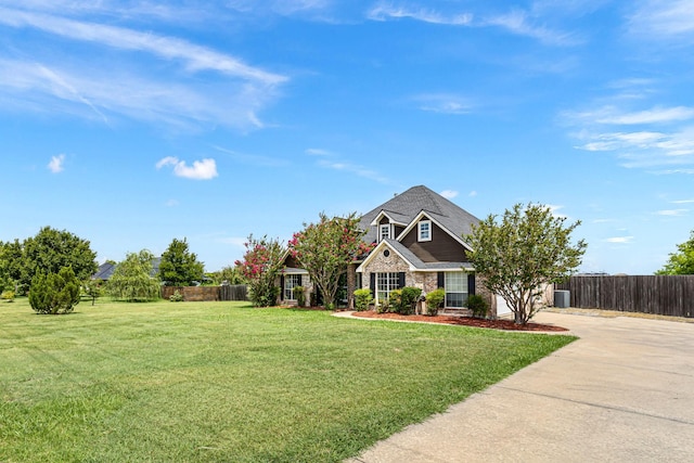 view of front of property featuring concrete driveway, fence, a front lawn, and stone siding