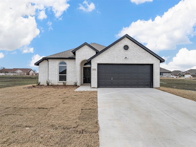 french provincial home featuring a garage, a front lawn, brick siding, and driveway