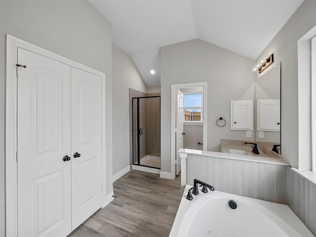 bathroom featuring a garden tub, a stall shower, wood finished floors, lofted ceiling, and vanity