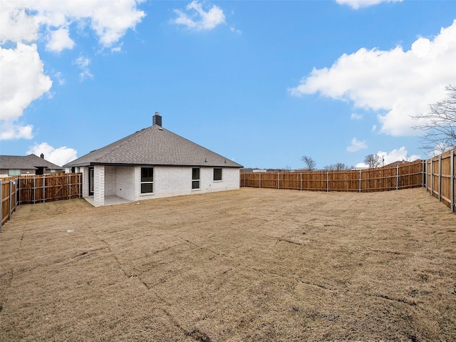 back of house featuring brick siding, a fenced backyard, and roof with shingles