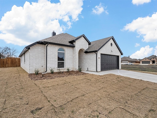 french country home with fence, concrete driveway, roof with shingles, a chimney, and a garage