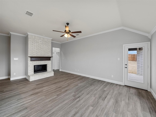 unfurnished living room with crown molding, a brick fireplace, a ceiling fan, and visible vents