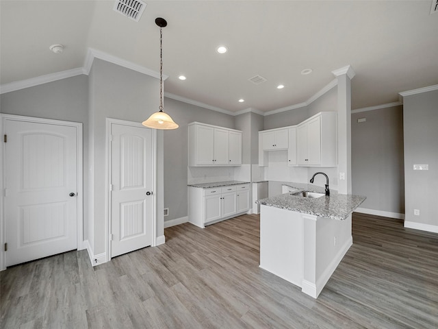 kitchen featuring light stone countertops, visible vents, a sink, white cabinetry, and light wood-type flooring