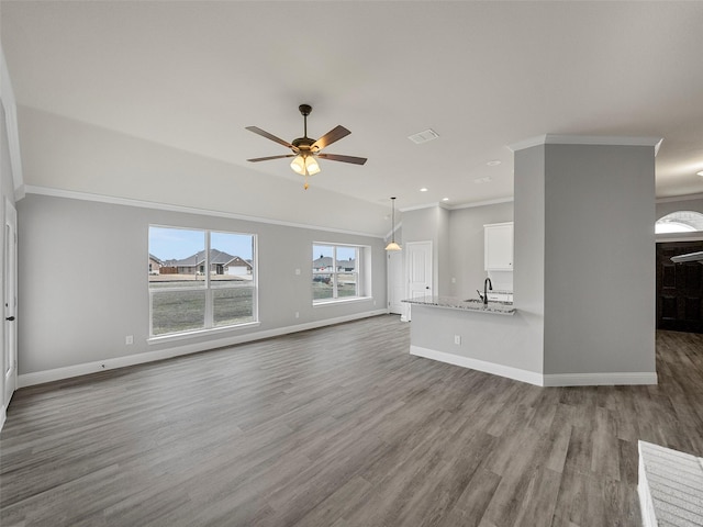 unfurnished living room featuring wood finished floors, visible vents, baseboards, ceiling fan, and crown molding