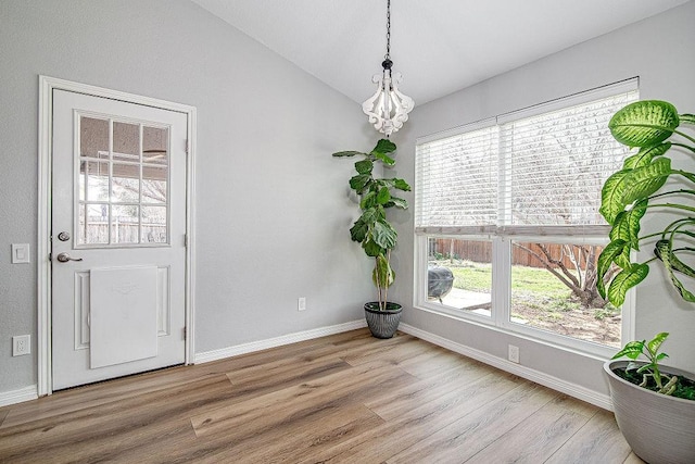 unfurnished dining area featuring baseboards, lofted ceiling, and wood finished floors