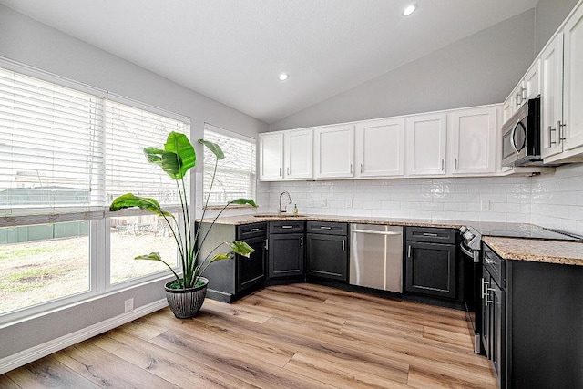 kitchen with white cabinetry, tasteful backsplash, appliances with stainless steel finishes, and vaulted ceiling