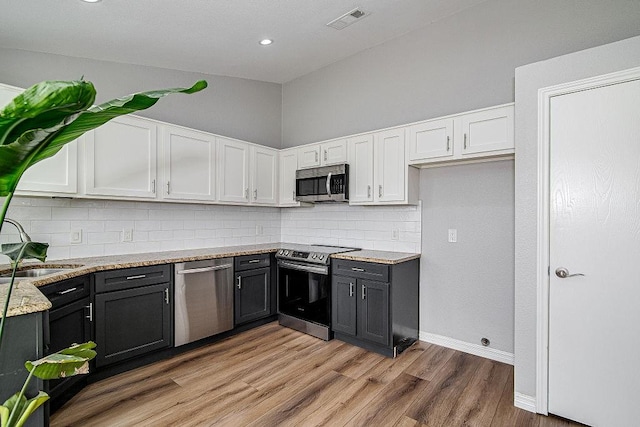 kitchen featuring visible vents, tasteful backsplash, white cabinetry, appliances with stainless steel finishes, and light wood finished floors