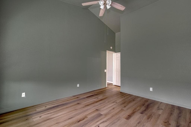 spare room with baseboards, high vaulted ceiling, a ceiling fan, and wood finished floors